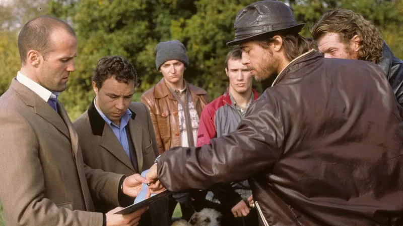 Five men in a field crowd round as one, in a flat cap and leather jacket, holds out his hand to close a deal