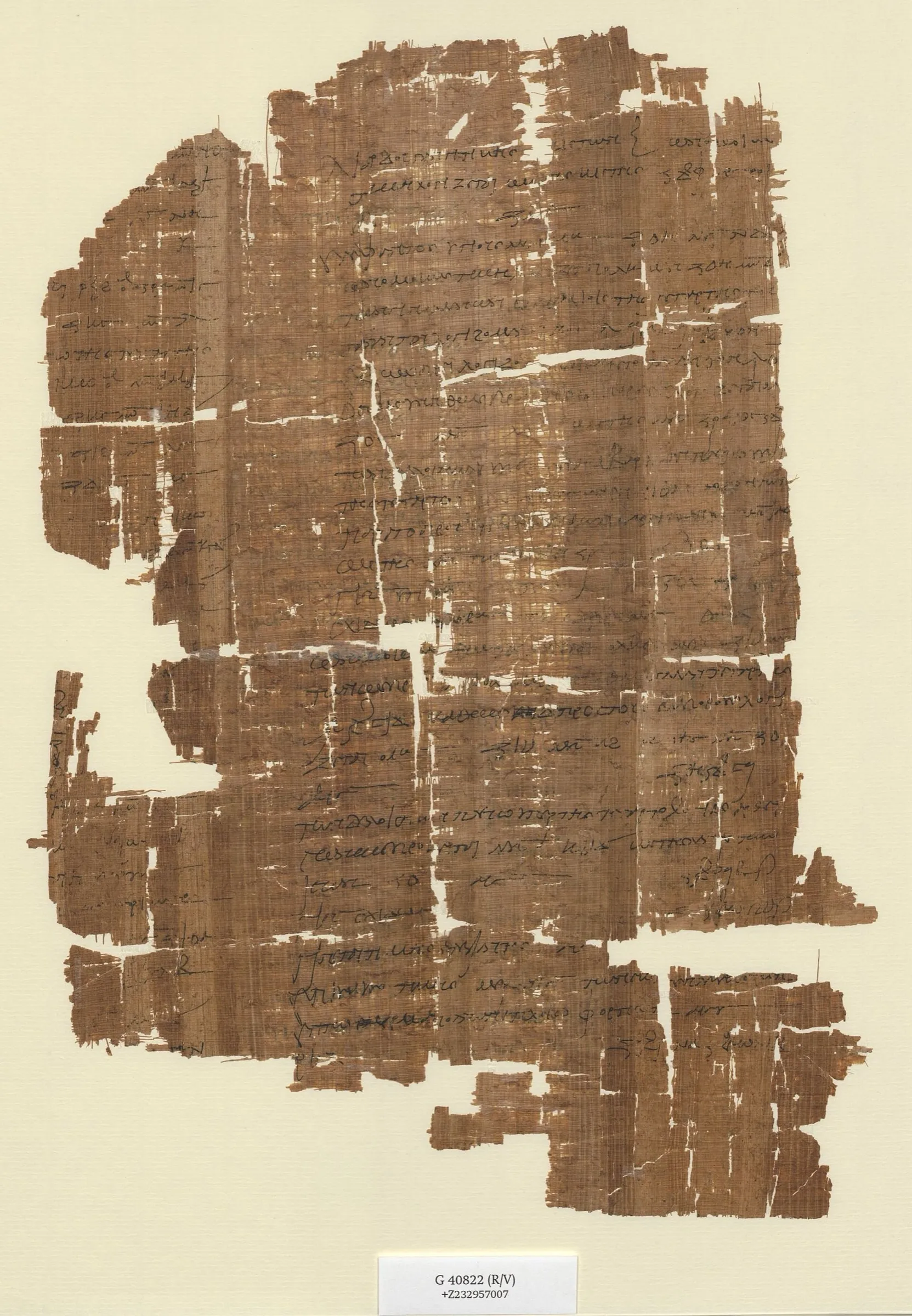 A fragment of ancient papyrus, brown and tattered at the edges, covered in close columns of handwritten Greek