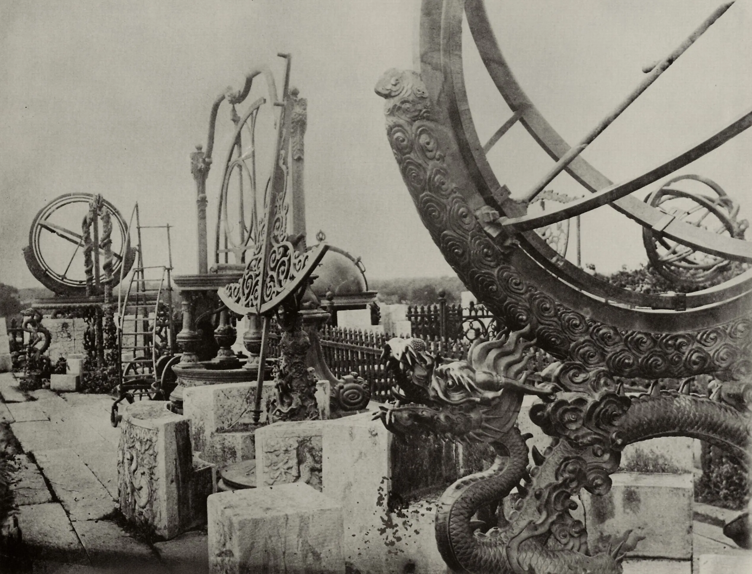 Large bronze astronomical instruments, armillary spheres and a celestial globe, standing on a walled terrace